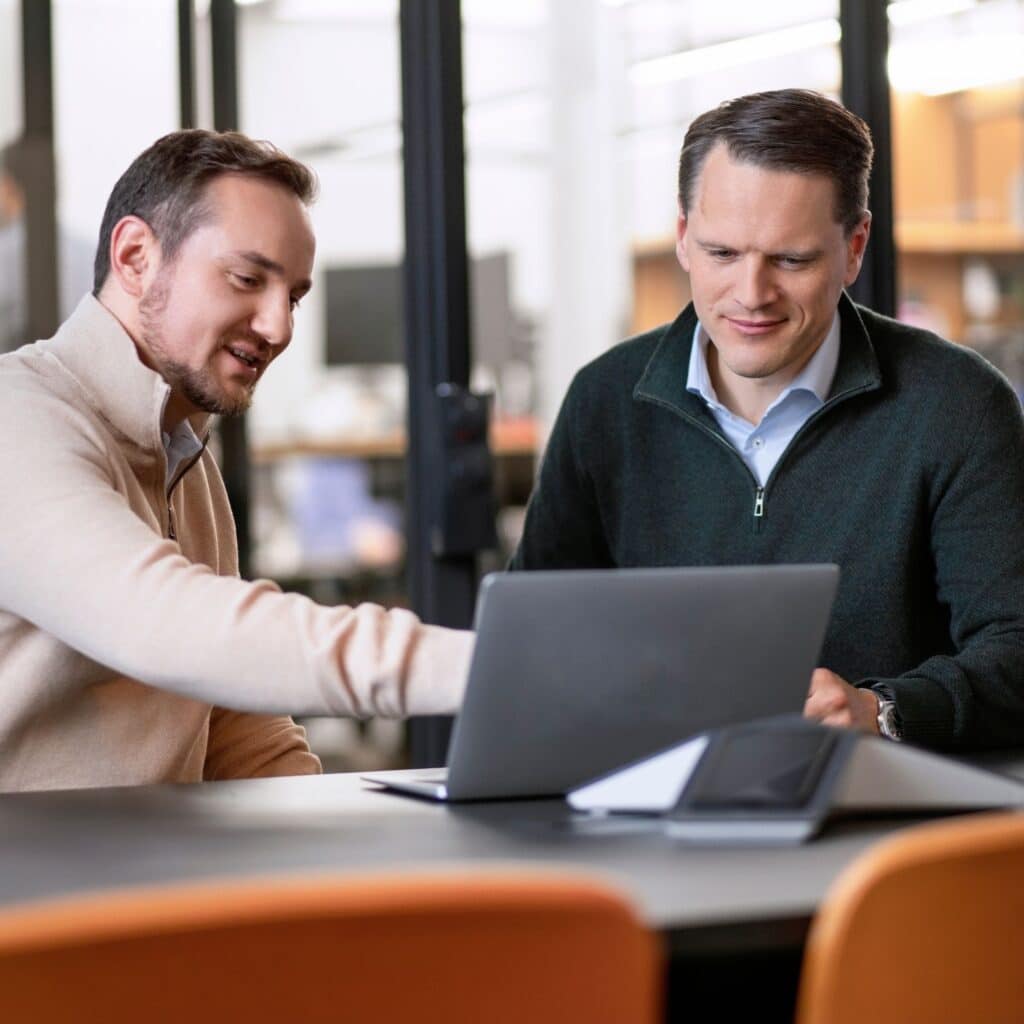 Peter Waleczek und Christoph Jost sitzen an einem Laptop.