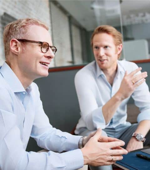 Zwei Mitarbeiter von FLEX Capital führen im Büro eine lebhafte Unterhaltung.